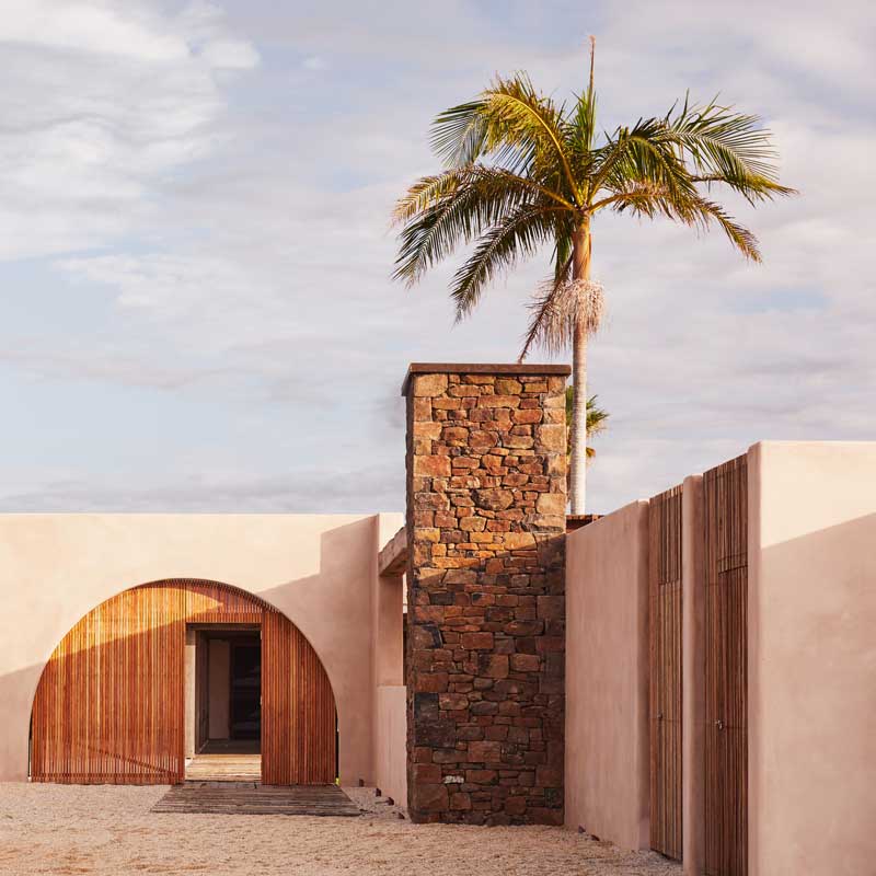 Entrance of a property featuring a timber arch doorway set in a rendered wall.