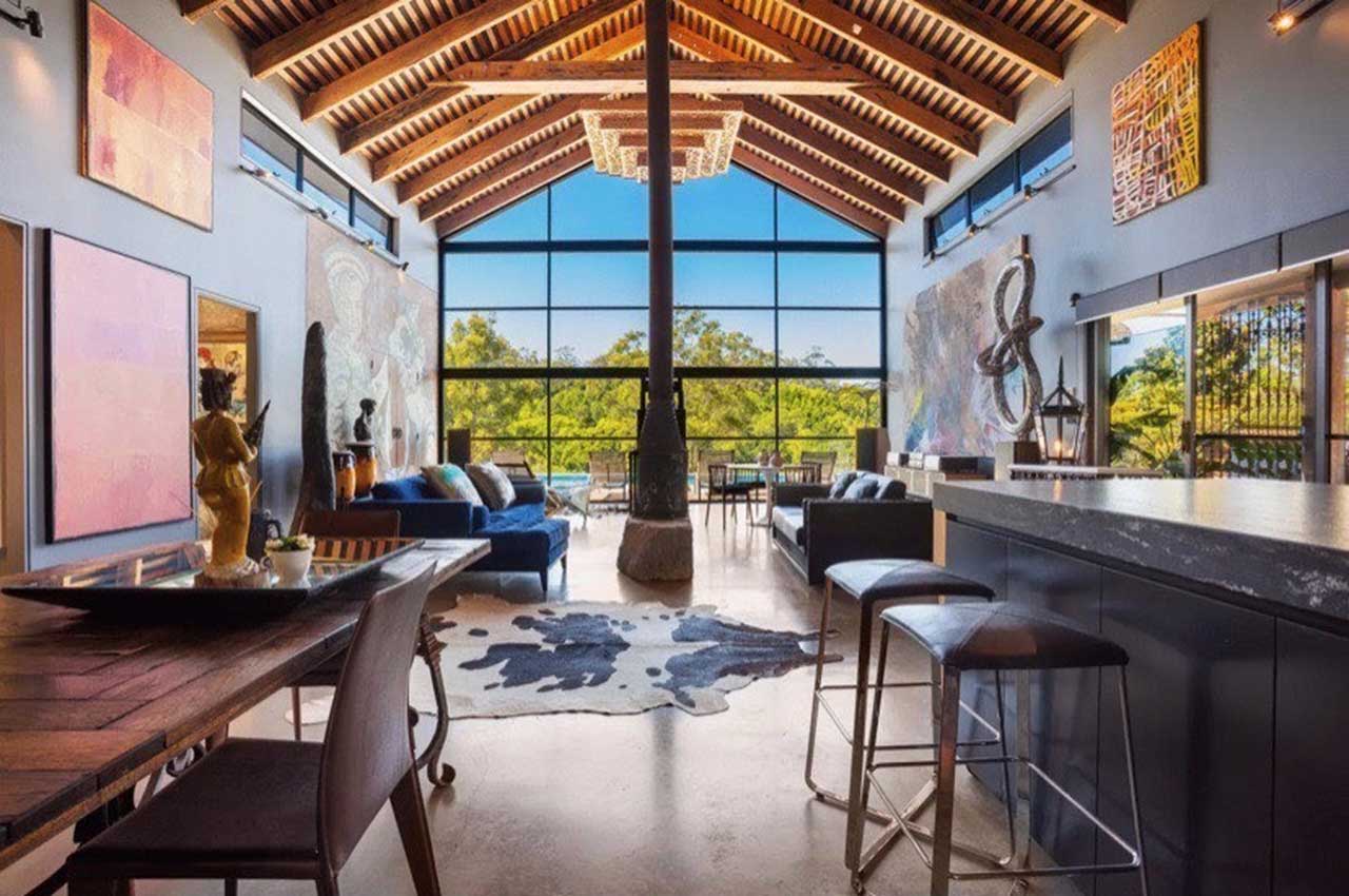 Image of Longwood Estate Byron Bay property lounge and bar room, showcasing timber trusses and floor-to-ceiling window, overlooking the pool.